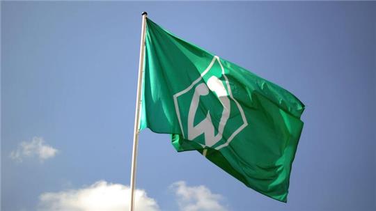 Eine Fahne mit dem Vereinslogo des Fußball-Bundesligisten SV Werder Bremen weht im Wind.