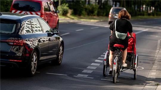Eine Fahrradfahrerin fährt mit einem Lastenfahrrad. Diese werden oft für den Transport von Kindern benutzt.