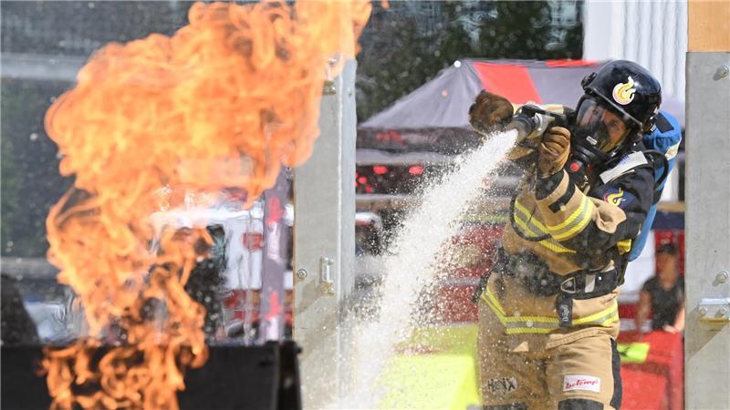 Eine Feuerwehrfrau löscht bei der Messe Interschutz einen kleinen Brand im Rahmen des Wettbewerbes Firefit Europameisterschaft. 