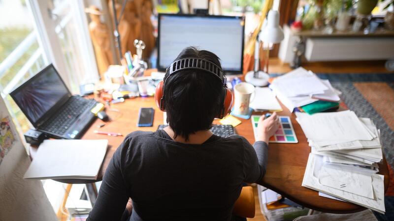 Eine Frau arbeitet mit Hörschutz im Homeoffice.