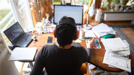 Eine Frau arbeitet mit Hörschutz im Homeoffice.