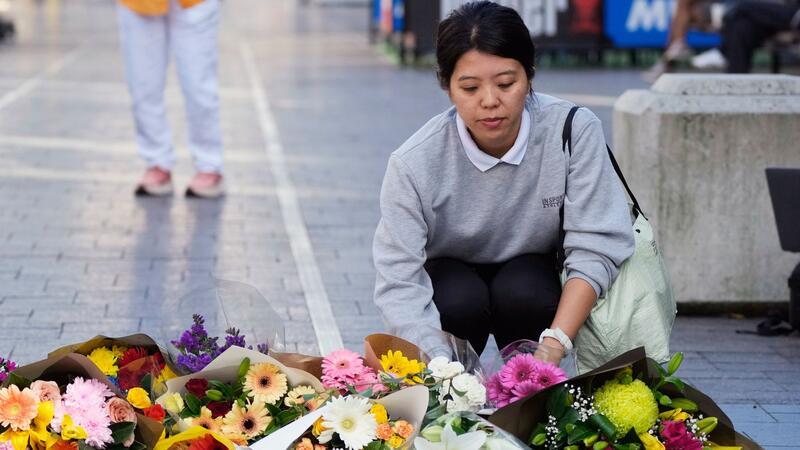 „Viele Leben gerettet“ - Polizistin als Heldin gefeiert Eine Frau bringt Blumen zu einer improvisierten Gedenkstätte an der Bondi Junction.
