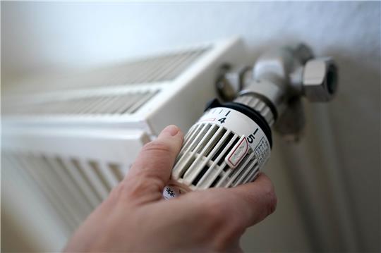 Eine Frau dreht an einem Heizungsthermostat.  Foto: Marcus Brandt/dpa