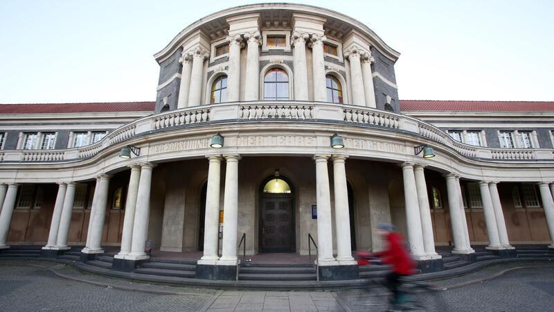 Labor zur Manuskriptforschung der Uni reist nach Indien Eine Frau fährt mit einem Fahrrad an dem Hauptgebäude der Universität Hamburg vorbei.
