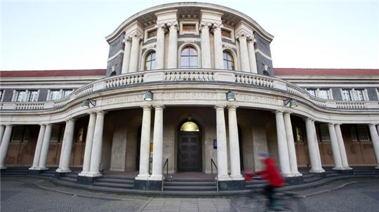 Eine Frau fährt mit einem Fahrrad an dem Hauptgebäude der Universität Hamburg vorbei.