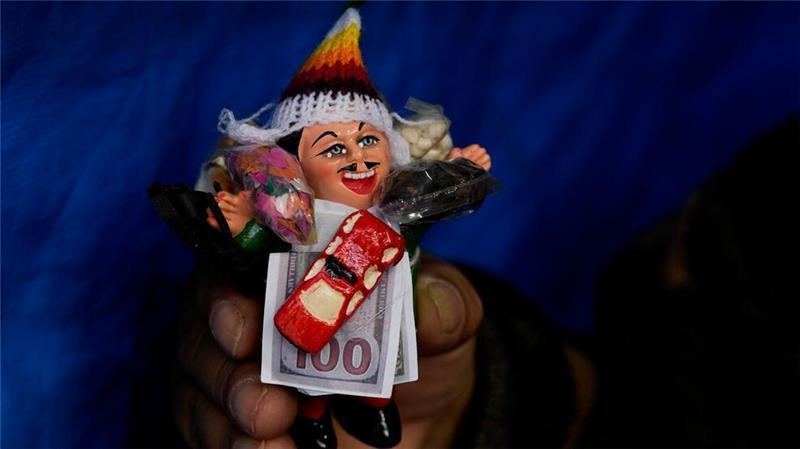 Eine Frau hält eine Miniatur von Ekeko, dem andinen Gott des Überflusses und der Fruchtbarkeit, während des jährlichen Alasita-Marktes in La Paz in Bolivien.