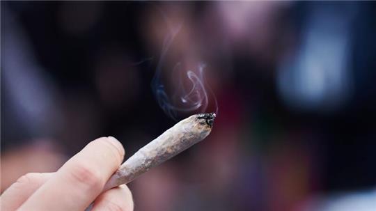 Eine Frau hält einen Joint in der Hand.