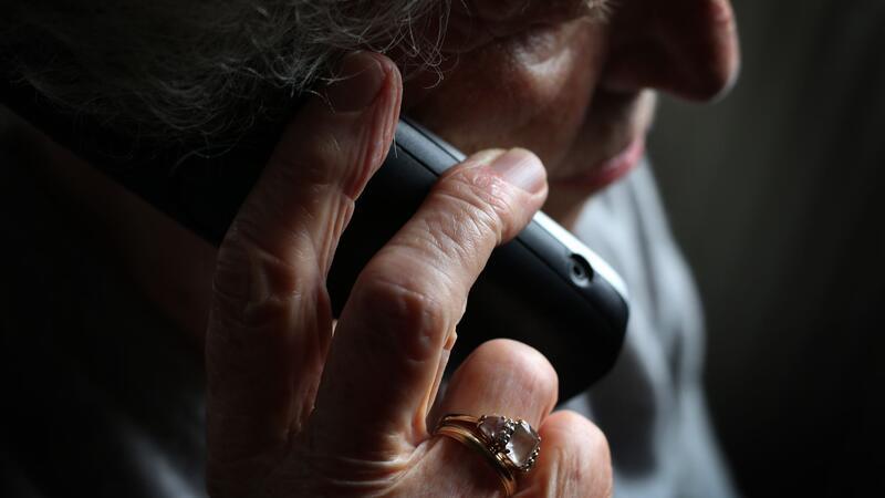 Eine Frau hält sich ein Telefon an ihr Ohr.