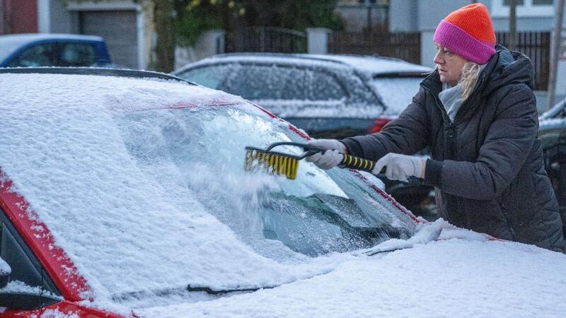 Erstes Schnee-Wochenende: Vom Winterzauber und den Unfällen Eine Frau in München befreit am frühen Morgen ein Auto von Schnee und Eis. Auch in den kommenden Tagen soll es winterlich bleiben.