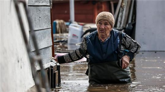 Eine Frau in der Nähe ihres Hauses in einem überschwemmten Gebiet in Orenburg, Russland.