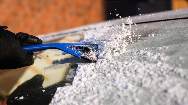 Eine Frau kratzt bei Temperaturen deutlich unter dem Gefrierpunkt Eis von der Windschutzscheibe eines Autos in der Region Hannover.