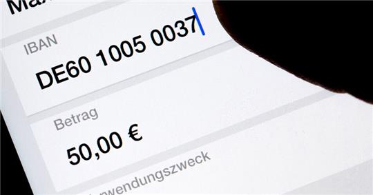 Eine Frau nutzt auf ihrem Smartphone eine App, um im Online-Banking eine SEPA-Überweisung zu veranlassen (gestellte Szene). Foto: Monika Skolimowska/dpa-Zentralbild/dpa