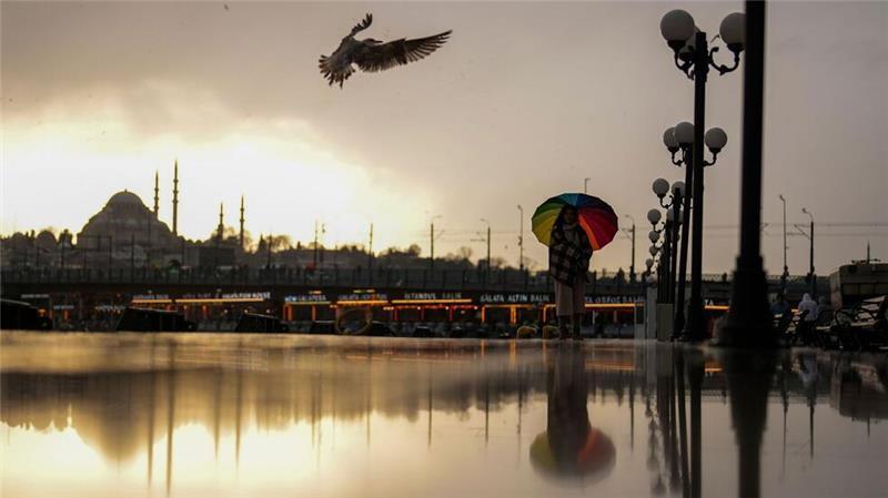Eine Frau schützt sich mit einem Regenschirm vor leichtem Schneefall an der Strandpromenade von Karakoy.