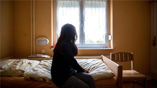 Eine Frau sitzt in einem Frauenhaus auf einem Bett. Tausende Frauen und Kinder haben auch 2022 zeitweilig Schutz in Schutzeinrichtungen gesucht.
