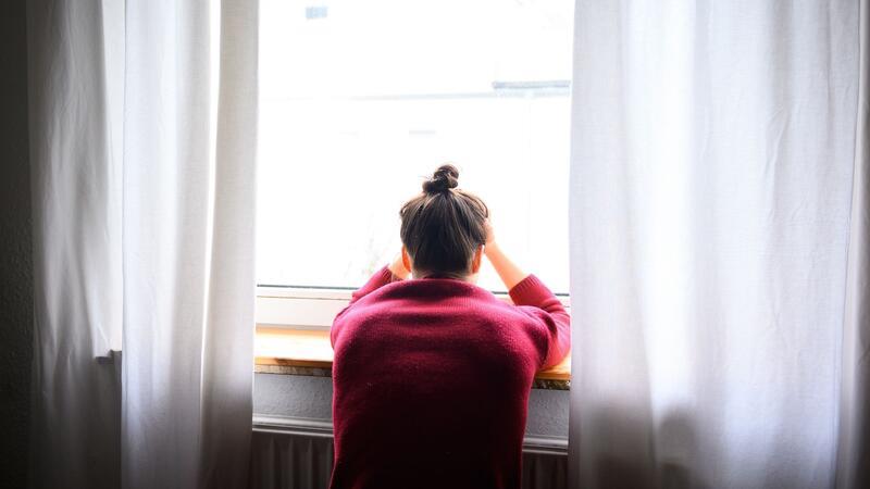 Depressionen nach der Geburt: Hier bekommen Mütter Hilfe Eine Frau sitzt mit Kopf in den Händen am Fenster.
