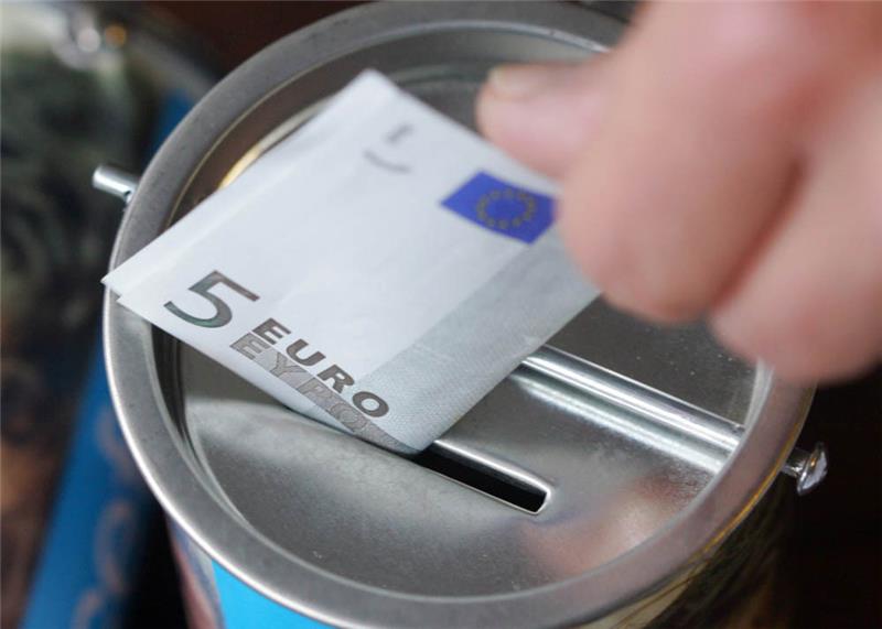 Eine Frau steckt einen Geldschein in eine Spendendose. Symbolbild: Bernd Thissen/dpa