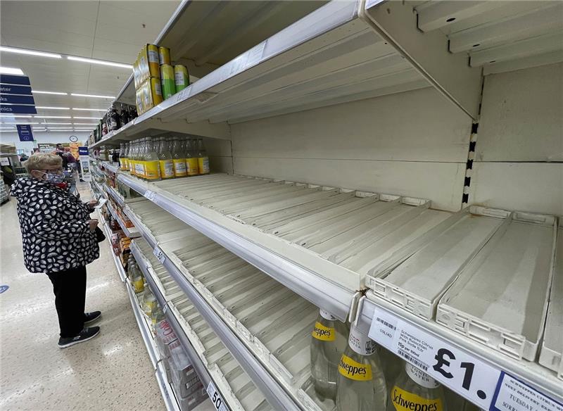 Eine Frau steht vor beinah leeren Regalen in einem Supermarkt in Großbritannien. Foto: Frank Augstein/AP/dpa