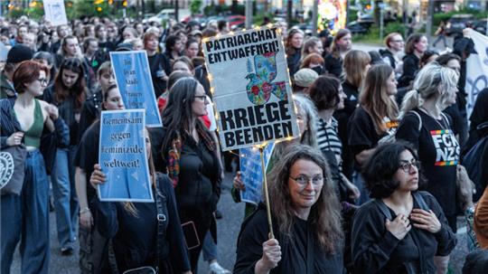 Eine Frau trägt ein Schild mit der Aufschrift «Patriarchat entwaffnen. Kriege beenden». Sie demonstriert mit anderen auf der traditionellen Walpurgisnacht-Demonstration unter dem Motto «Take back the Night» durch das Schanzenviertel und St.Pauli.