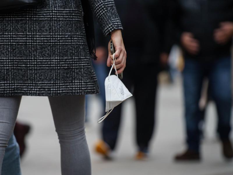 Eine Frau trägt eine FFP2-Maske in der Hand. (Symbolbild). Foto: Frank Rumpenhorst/dpa