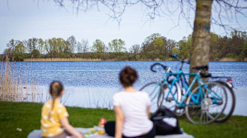 Sonniges Wetter in Niedersachsen und Bremen: Waldbrandgefahr Eine Frau und ein Kind sitzen bei sonnigem Wetter am Ufer vom Hufeisensee in der Region Hannover.