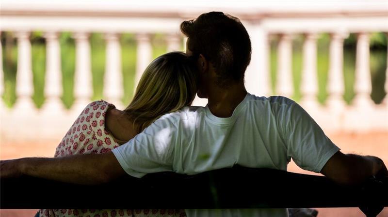 Eine Frau und ein Mann sitzen zusammen auf einer Parkbank (gestellte Szene). 