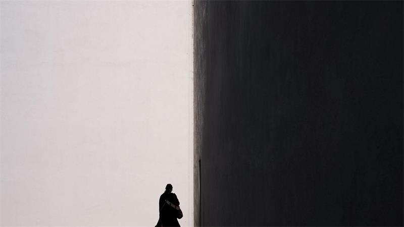 Eine Frau zeichnet sich als Silhouette vor der sonnenbeschienenen Fassade eines Gebäudes in in Kalifornien ab.