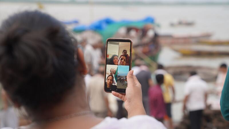 Eine Frau zeigt ihren Angehörigen, die nicht anwesend sein können, in einem Videoanruf das Verbrennungsritual eines verstorbenen Familienmitglieds.