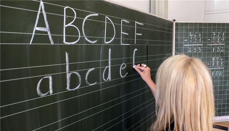 Eine Grundschülerin in Hamburg die ersten Buchstaben des Alphabets auf eine Schultafel in einem Klassenzimmer.