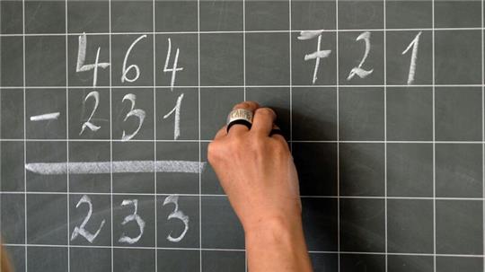 Eine Hamburger Lehrerin schreibt Mathematikaufgaben auf eine Schultafel.