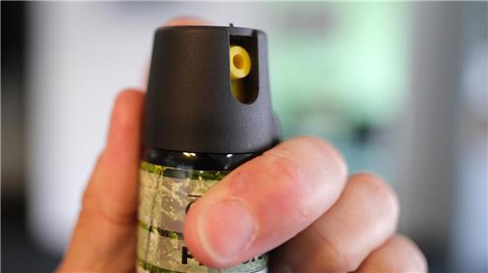 Eine Hand hält eine Kartusche mit Pfefferspray.