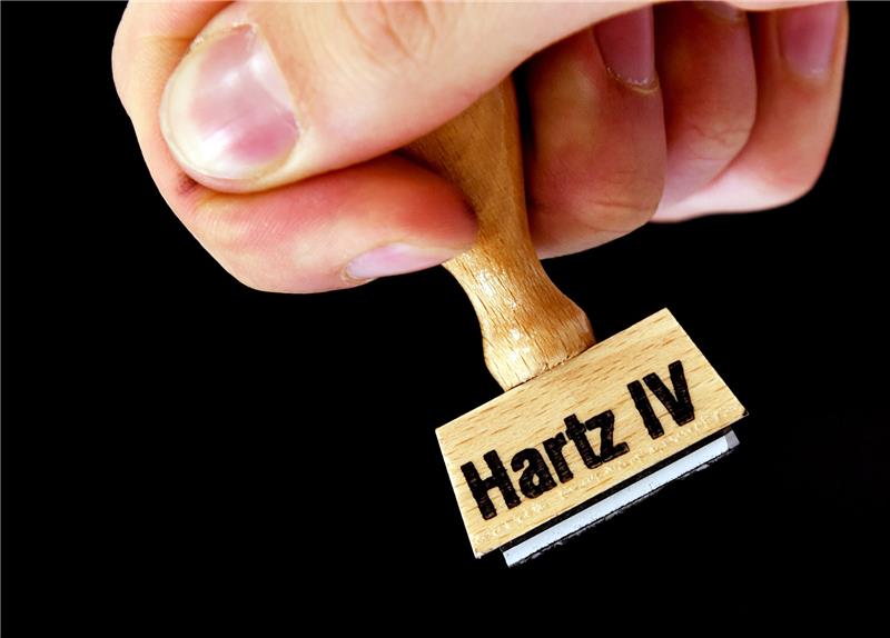 Eine Hand hält einen Stempel mit der Aufschrift «Hartz IV». Foto: Ralf Hirschberger/dpa-Zentralbild/dpa