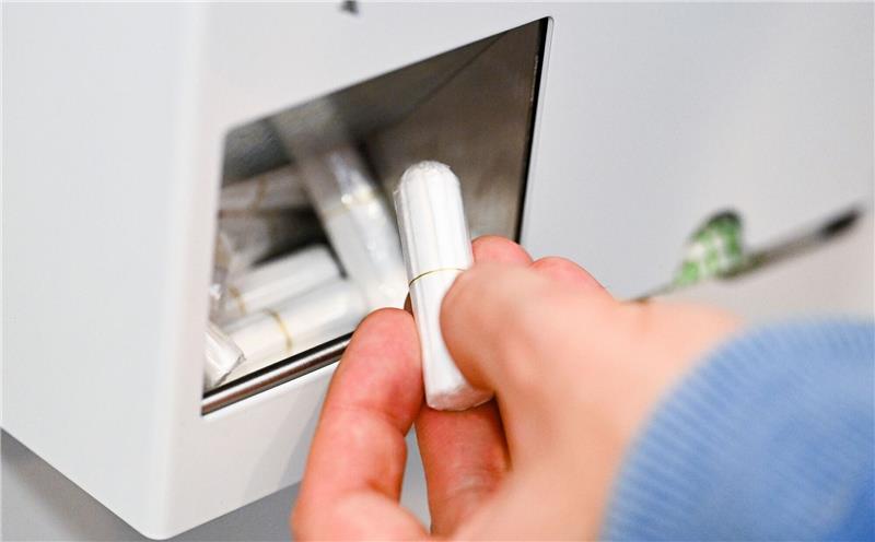 Eine Hand nimmt einen Tampon aus einem Tampon-Spender. Foto: dpa