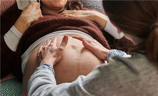 Eine Hebamme tastet in ihrer Praxis den Bauch einer schwangeren Frau ab. (Archivbild)