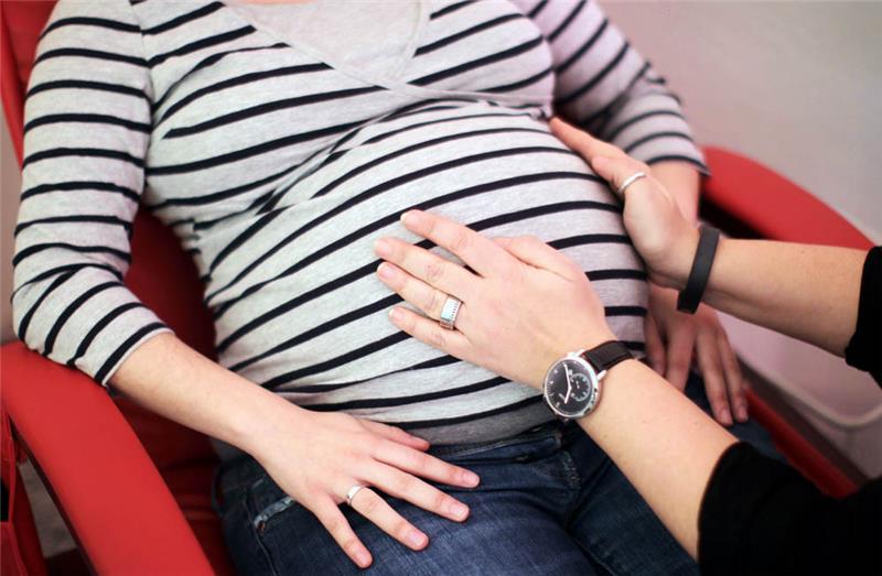 Eine Hebamme untersucht eine schwangere Frau. Foto: Fredrik Von Erichsen/dpa