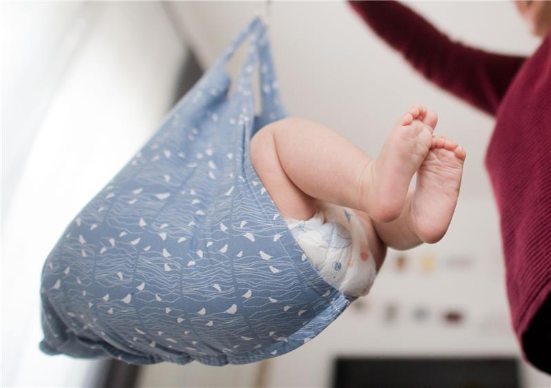 Eine Hebamme wiegt im Rahmen der Nachsorge ein Baby (gestellte Szene). Foto: Julian Stratenschulte/dpa