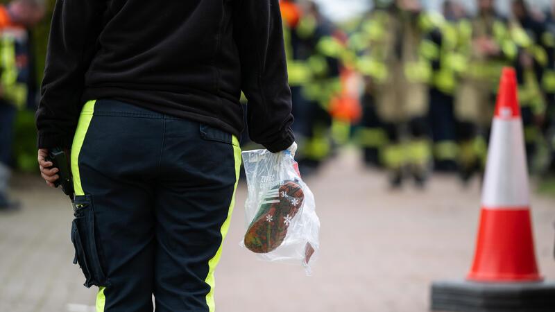 Eine Hundeführerin hält einen Beutel mit Arians Schuhen für die Suchhunde in der Hand.