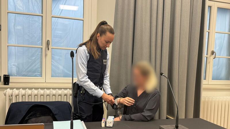 Eine Justizmitarbeiterin nimmt der Angeklagten beim Prozessauftakt vor dem Landgericht Ravensburg die Handschellen ab.