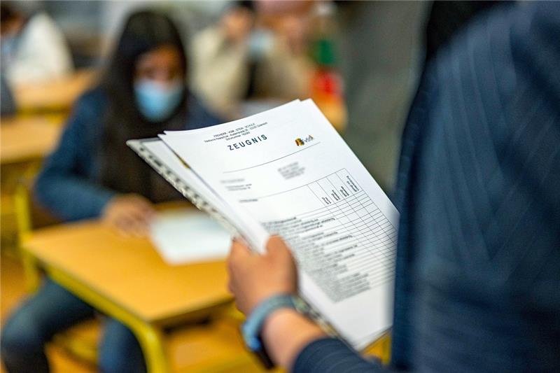 Eine Klassenlehrerin verteilt Zeugnisse zum ersten Halbjahr. Foto: David Inderlied/dpa