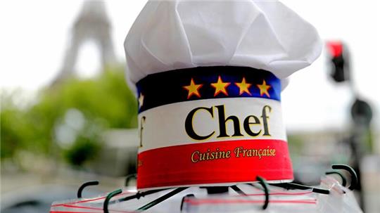 Eine Kochmütze wird an einem Souvenirstand beim Eiffelturm angeboten. In Frankreichs Gastronomie werden viele Stellen von Ausländern besetzt.