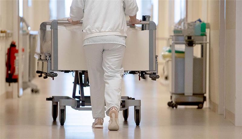 Eine Krankenpflegerin schiebt ein Krankenbett durch einen Flur. Am Donnerstag beriet die Bund-Länder-Arbeitsgruppe über die Umsetzung der Reformvorschläge zur Krankenhausfinanzierung, die von einer für das Thema eingesetzten Expertenkommission am 6. Dezember vorgestellt wurden. Foto: Marijan Murat/dpa