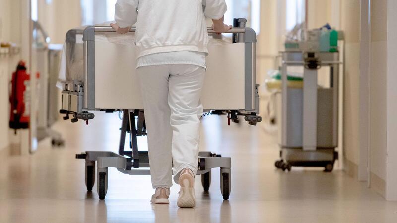 Länder pochen auf Änderungen bei Klinikreform Eine Krankenpflegerin schiebt ein Krankenbett durch einen Krankenhausflur.