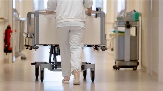 Eine Krankenpflegerin schiebt ein Krankenbett durch einen Krankenhausflur.