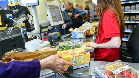 Eine Kundin nimmt in einem Supermarkt Waren vom Band an der Kasse, nachdem eine Kassiererin die Waren gescannt hat. Das Warten in der Schlange an der Kasse kann nervig sein (Symbolbild).