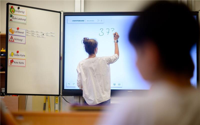 Erste Schulen in Niedersachsen legen Fächer zusammen Eine Lehrerin schreibt eine Mathematikaufgabe auf eine digitale Schultafel.