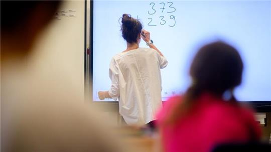 Eine Lehrerin schreibt eine Mathematikaufgabe auf eine digitale Schultafel im Klassenraum einer 4. Klasse einer Grundschule in der Region Hannover.