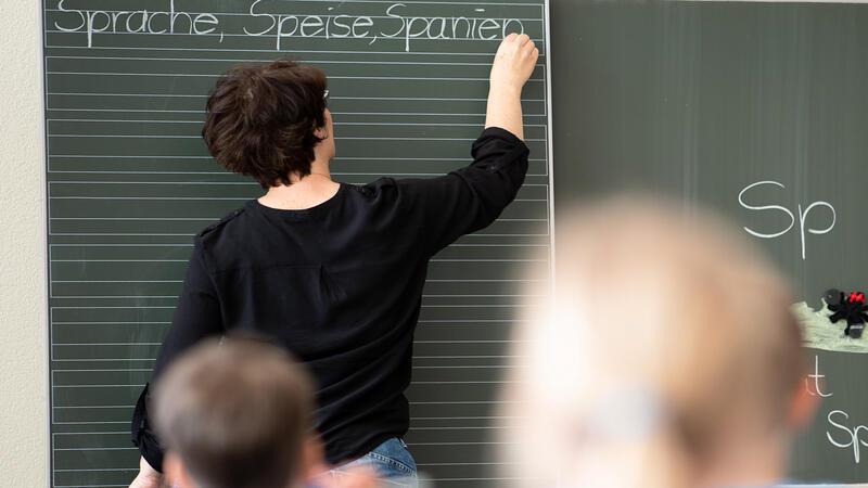Unterrichtsausfall: FDP fordert Transparenz bei der Lehrerversorgung Eine Lehrerin schreibt in einer Schule Worte an eine Tafel.