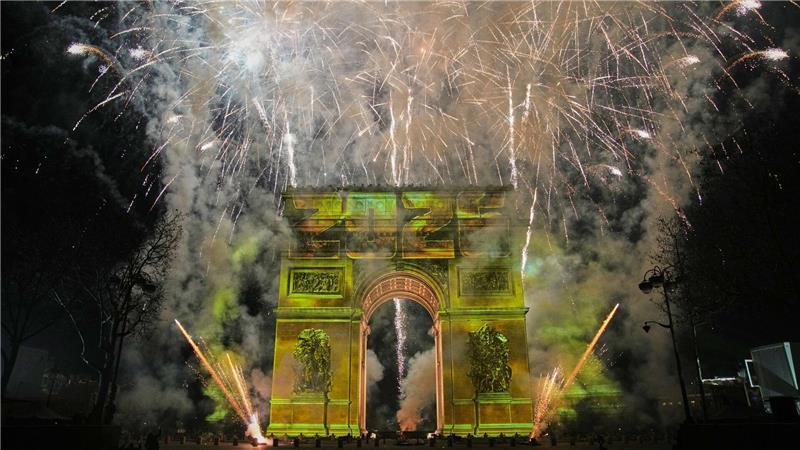 Eine Lichtshow wird auf den Arc de Triomphe projiziert, während ein Feuerwerk im Rahmen der Neujahrsfeierlichkeiten auf den Champs Elysees gezündet wird.