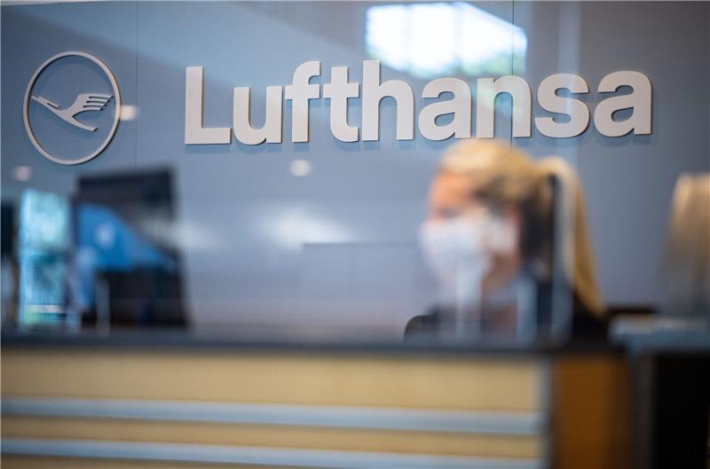 Eine Mitarbeiterin der Lufthansa sitzt mit ihrer Mund- und Nasenschutzmaske am Check-in im Flughafen Münster-Osnabrück.