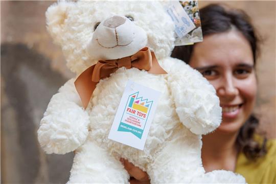 Eine Mitarbeiterin des Plüschtierherstellers Heunec präsentiert einen Stoffteddy, der mit dem Siegel der Fair Toys Organisation gekennzeichnet ist.
