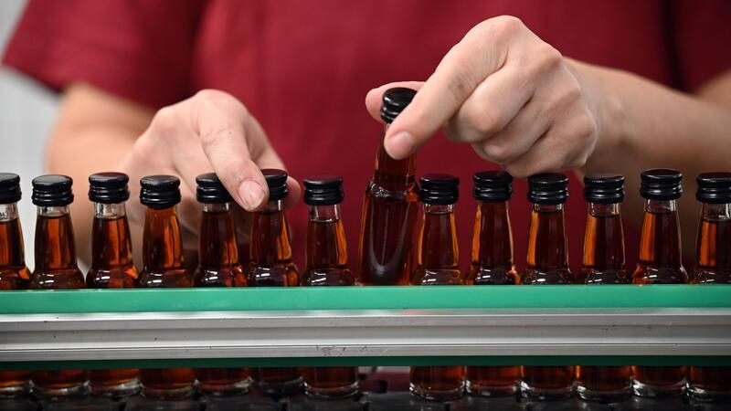 Eine Mitarbeiterin eines Spirituosenherstellers kontrolliert die abgefüllten Flaschen. Die Zurückhaltung beim Konsum macht sich auch bei den Spirituosen-Herstellern bemerkbar (Symbolbild).